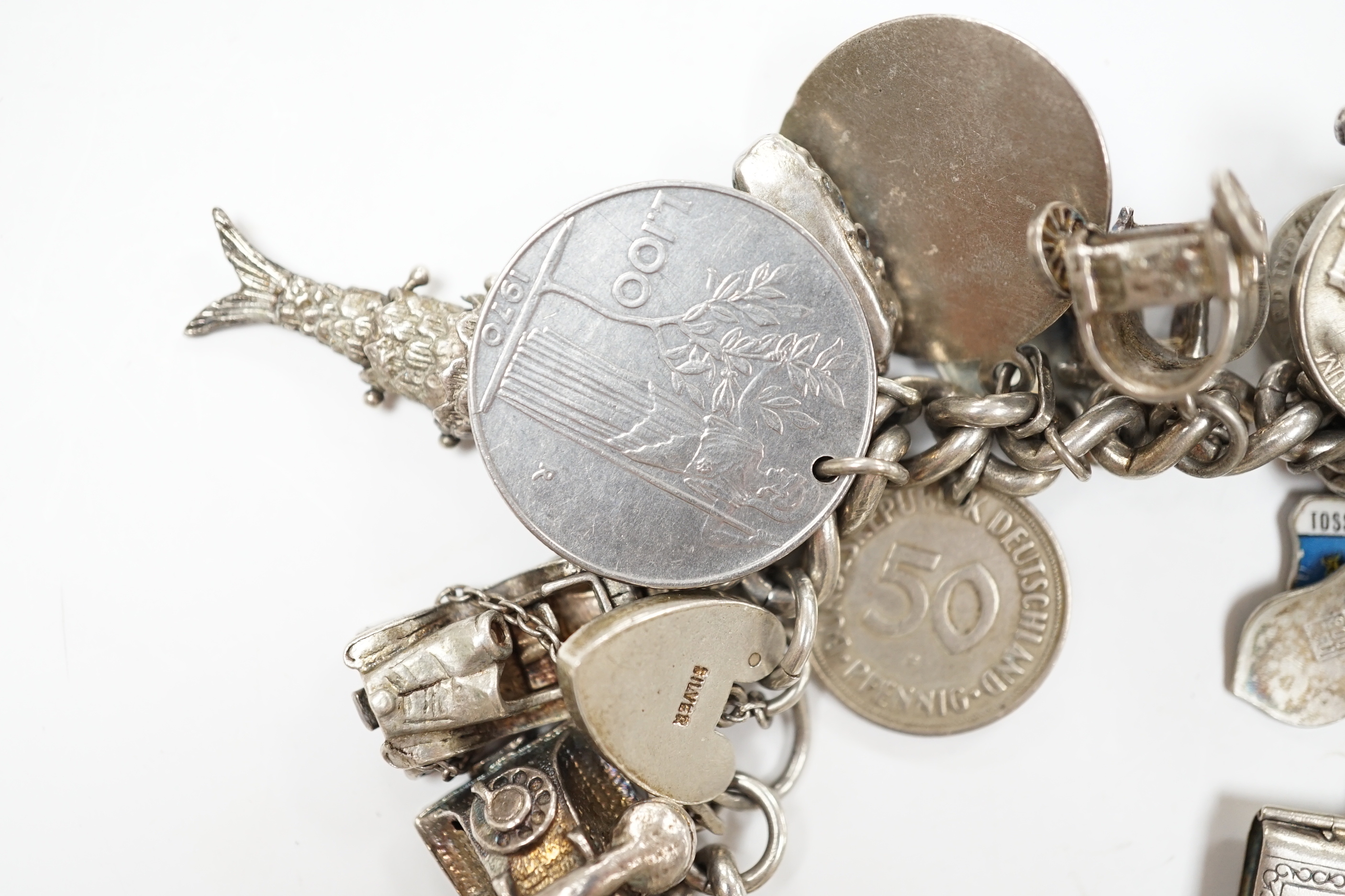 A silver charm bracelet, hung with assorted mainly white metal charms including tankard and Knight's helmet, two 'melted' ingots and a silver medallion.